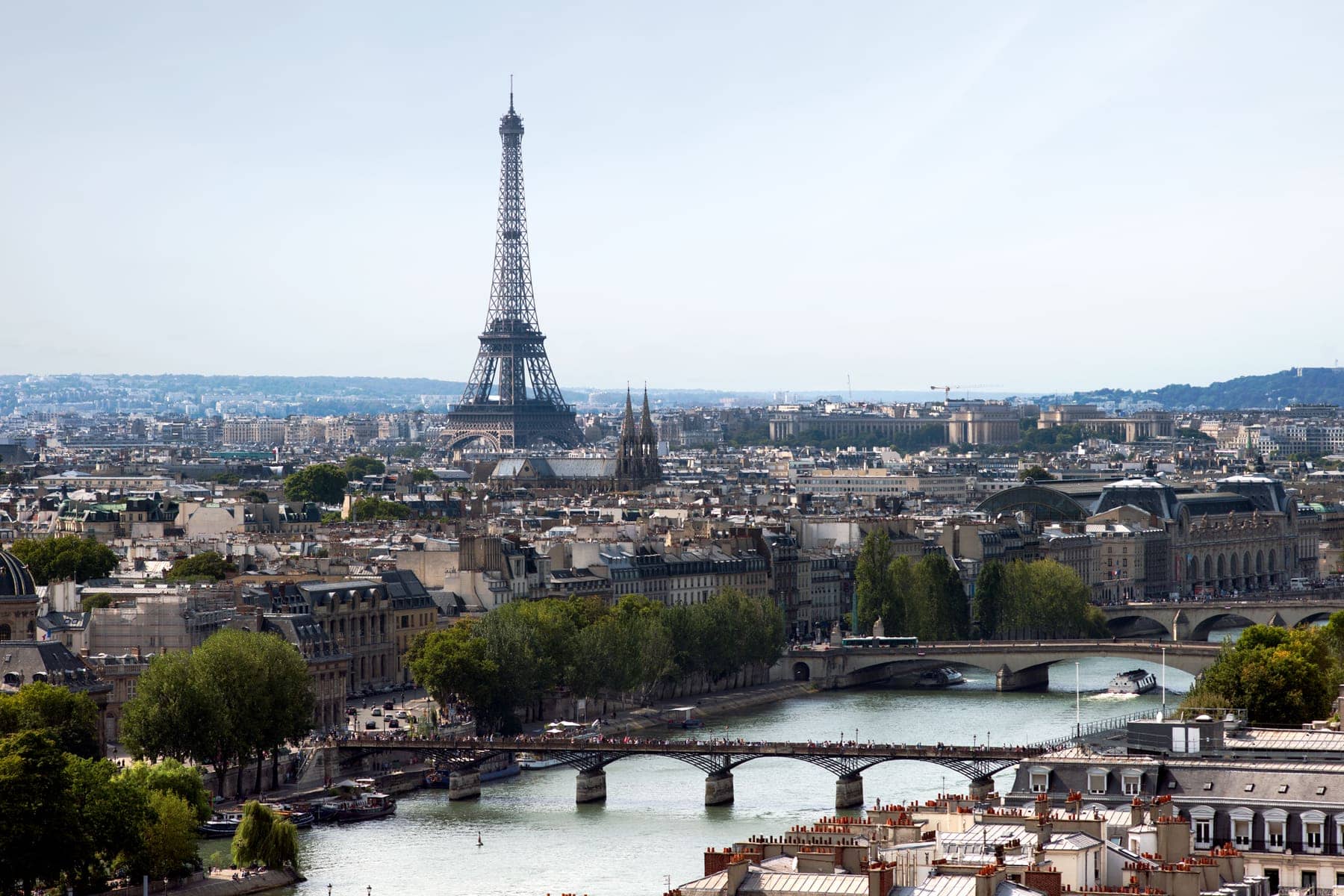 The Eiffel Tower rising above Paris rooftops, with the Seine and several bridges in the foreground