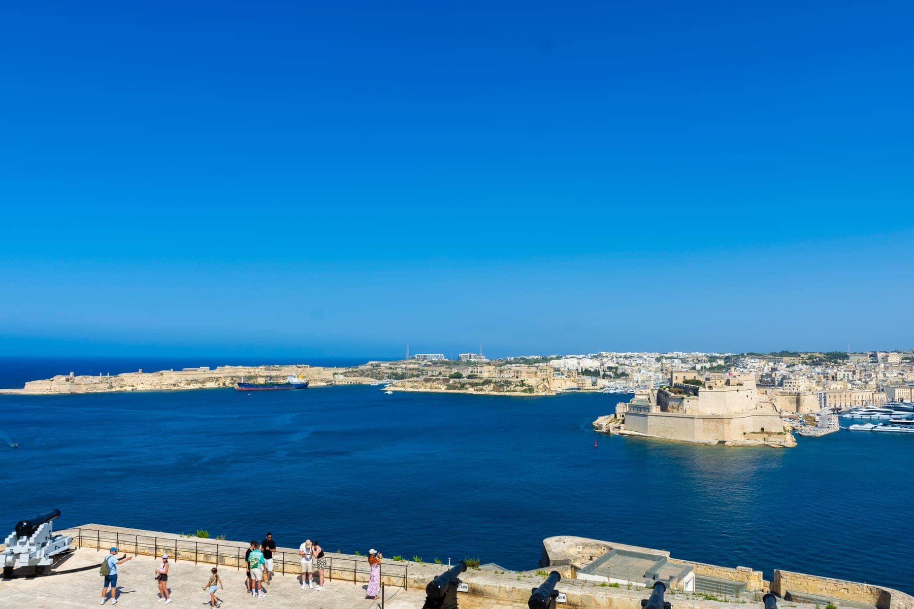 Blue waters of the Grand Harbour with a fortified peninsula and waterfront buildings, seen from a terrace in Valletta